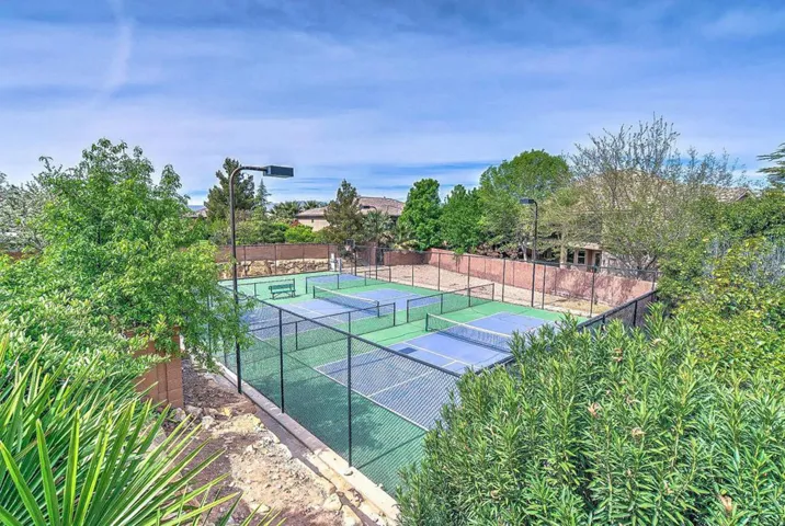 Resort-style recreational courts featuring multiple pickleball and tennis playing surfaces with professional-grade court markings, surrounded by mature landscaping and lush greenery
