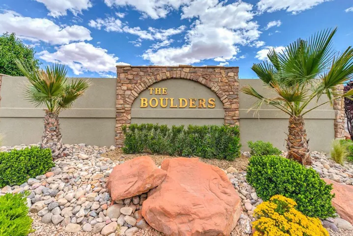 Stone archway with property name, desert landscaping, palm trees, and ground cover