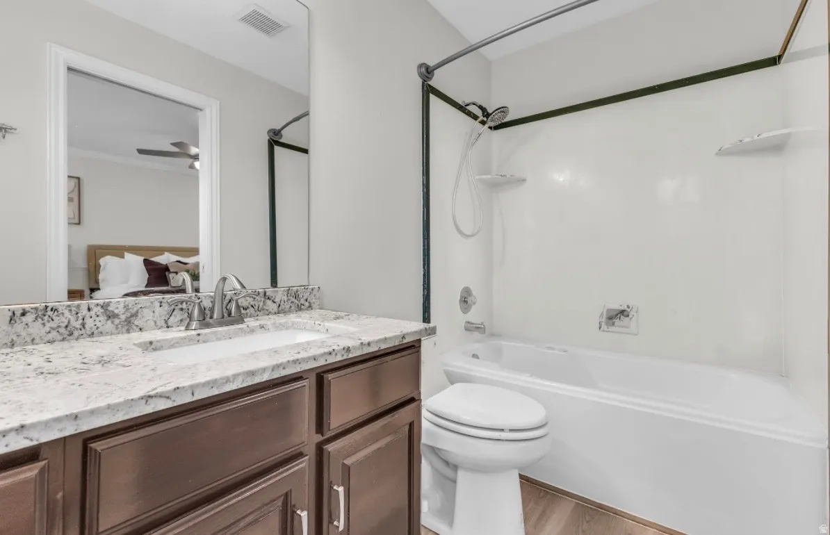 Dual-vanity bathroom featuring a speckled quartz countertop, wood-finish cabinetry with integrated storage, polished chrome fixtures, and a frameless glass-enclosed shower with white subway tile surround and soaking tub