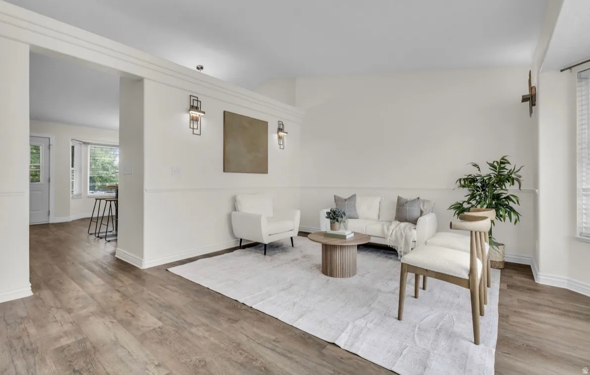 Wood-finish flooring throughout, white wall paneling, and contemporary wall sconces