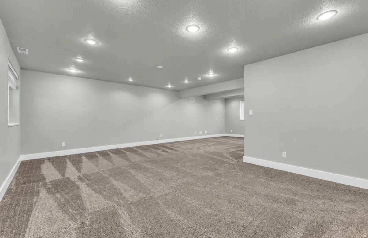 Expansive carpeted area with recessed lighting, light-toned walls, and white trim