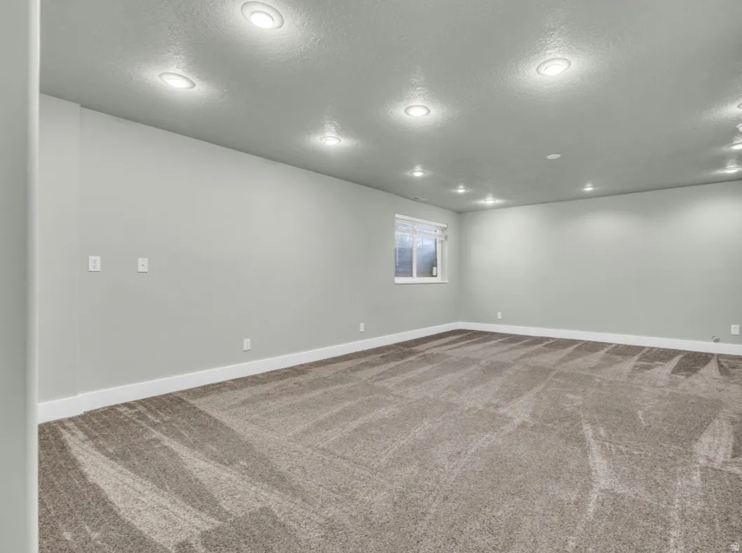 Spacious room with recessed lighting, light gray walls, and textured carpeting