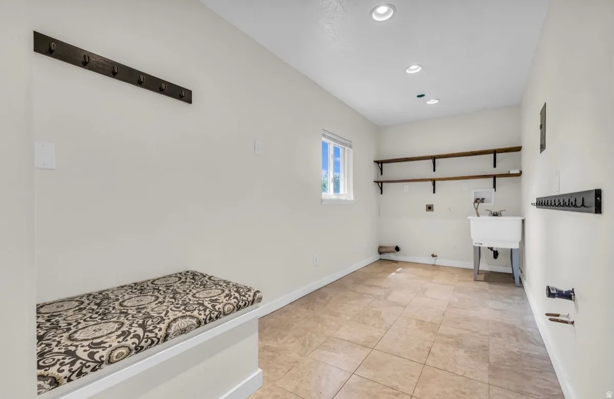 Utility room with tile flooring, built-in storage bench, and a utility sink