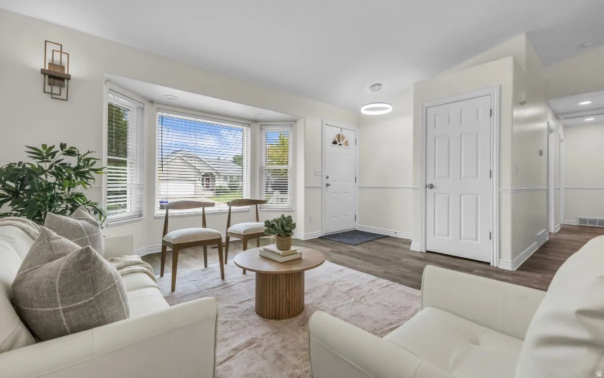 Bay windows with blinds, wood-finish flooring, white paneled doors, and a modern ceiling light fixture