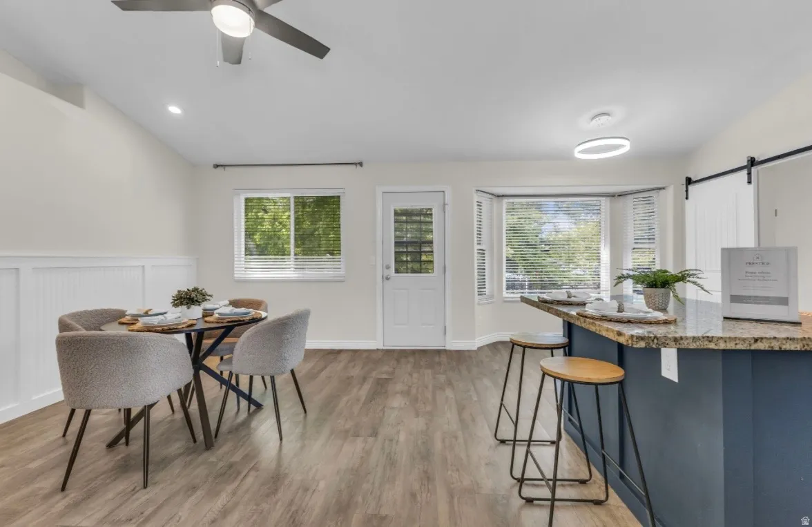 Wood-finish flooring, wainscoting, bay window, white paneled door, and recessed lighting