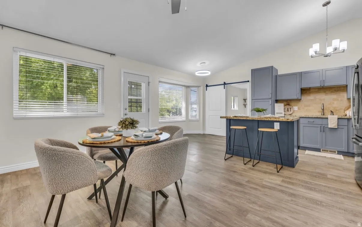 Open-concept living and dining area featuring wood-finish flooring, abundant natural light from multiple windows, and seamless integration with a chef's kitchen