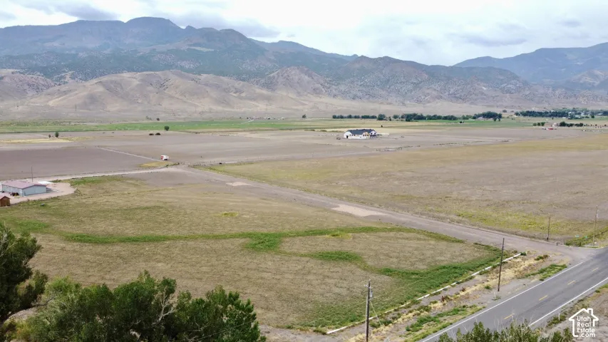 Expansive open land with a paved road boundary and distant mountain ranges