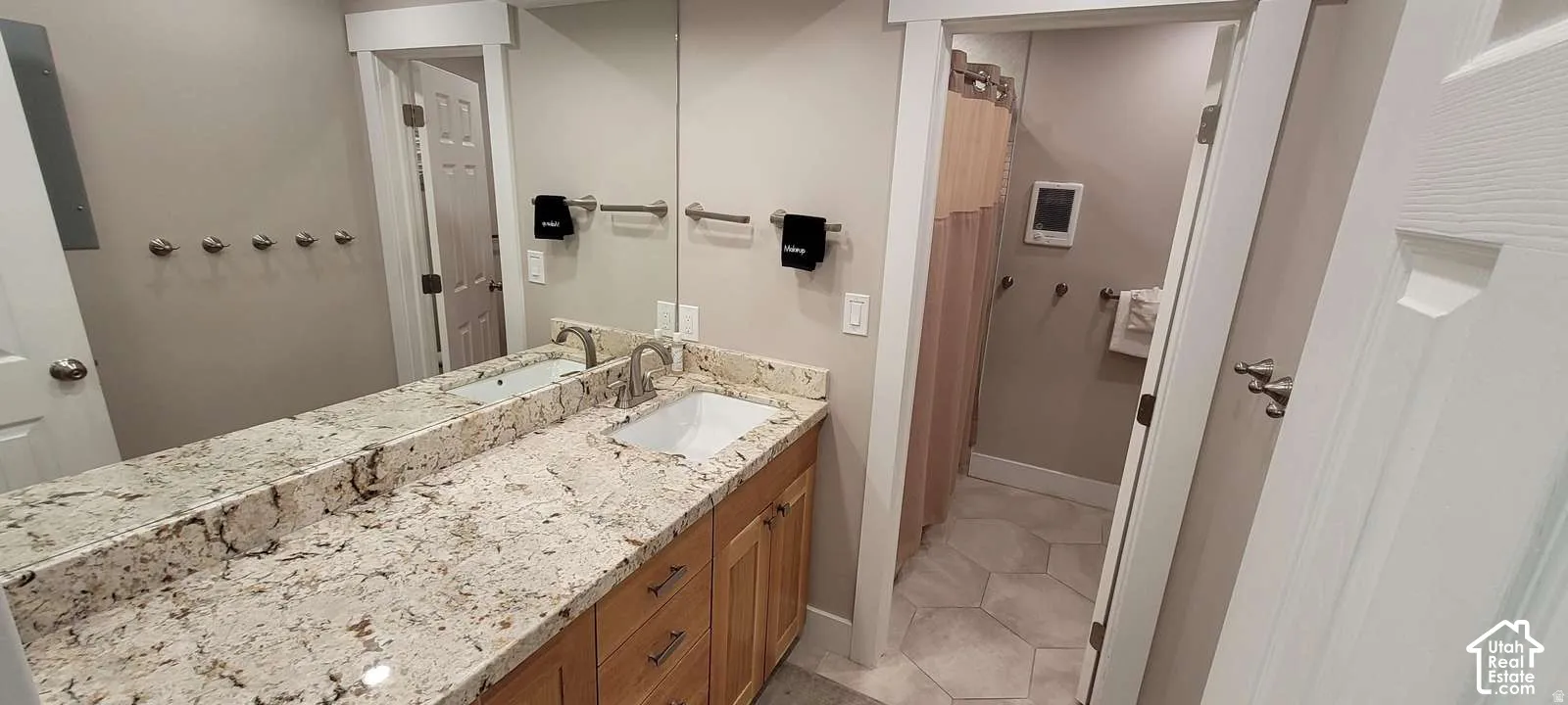 Dual sink vanity with stone-finish countertop, wood-finish cabinetry, and brushed nickel fixtures