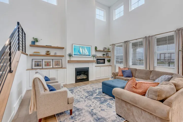 Two-story living area with a fireplace, built-in cabinetry, and wood-finish flooring