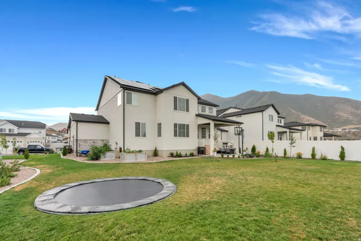 Expansive backyard with a manicured lawn, established landscaping, and a mountain backdrop