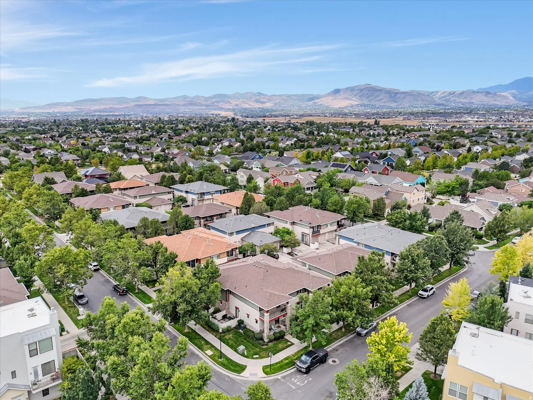 Aerial view of the property and community featuring custom-built homes with varied architectural styles, mature landscaping throughout the neighborhood, and mountain backdrop
