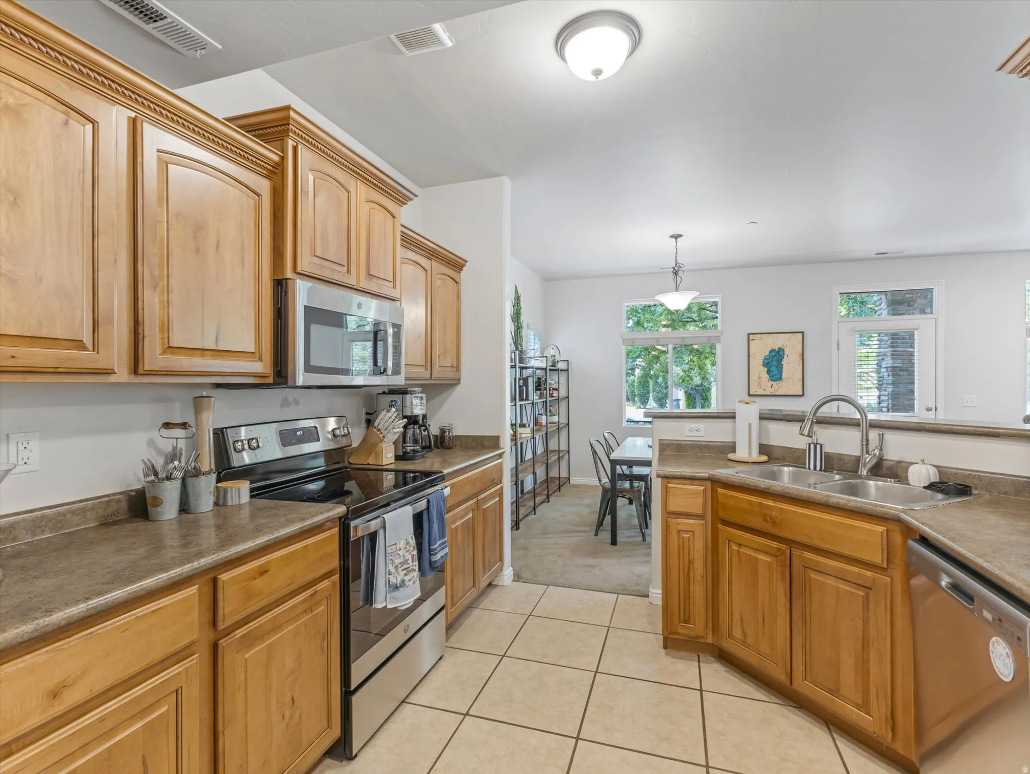 Kitchen featuring wood cabinetry, stainless steel appliances, a double basin sink, and tile flooring
