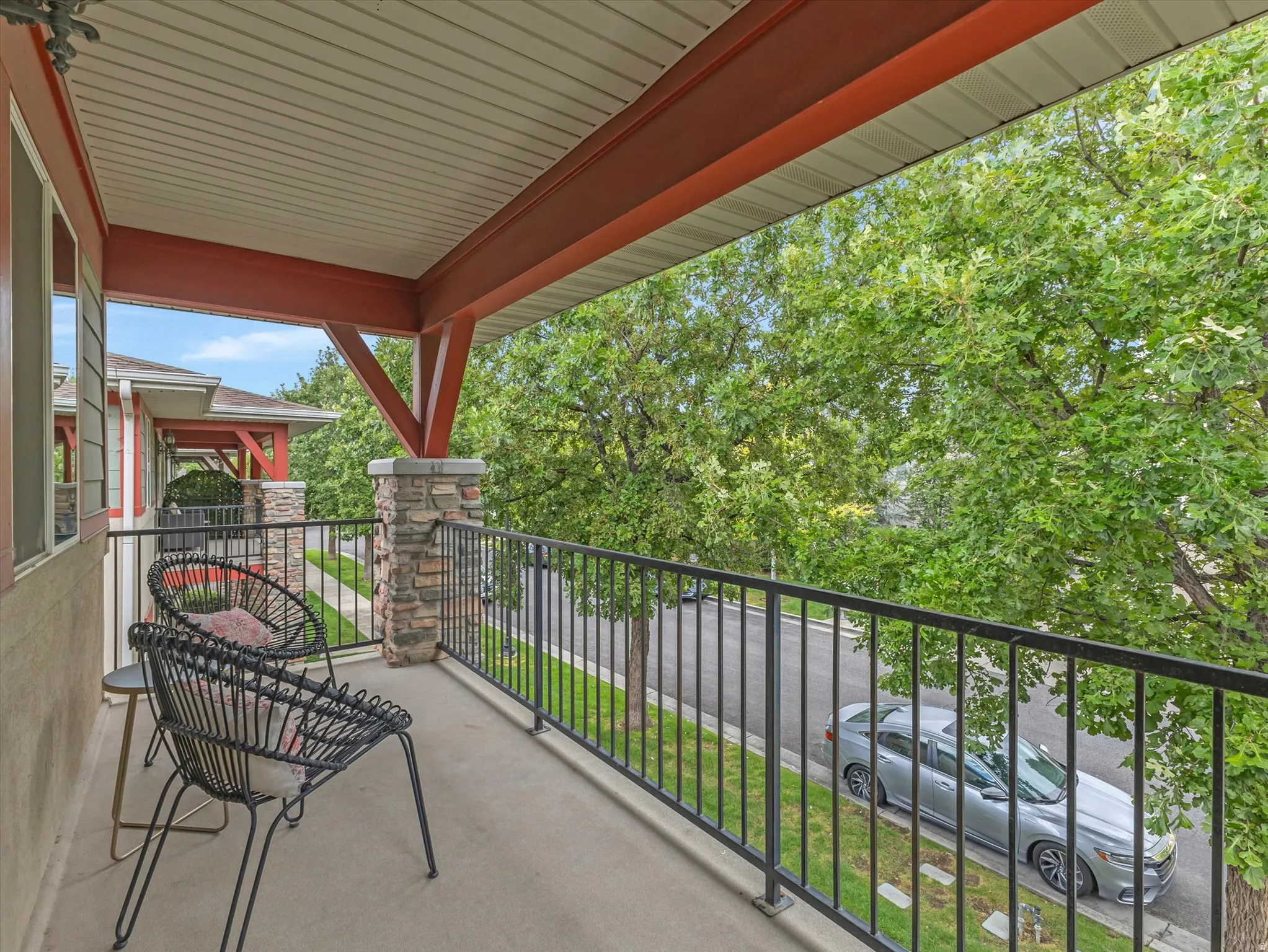 Balcony with a concrete surface, black metal railing, and stone-clad support pillars