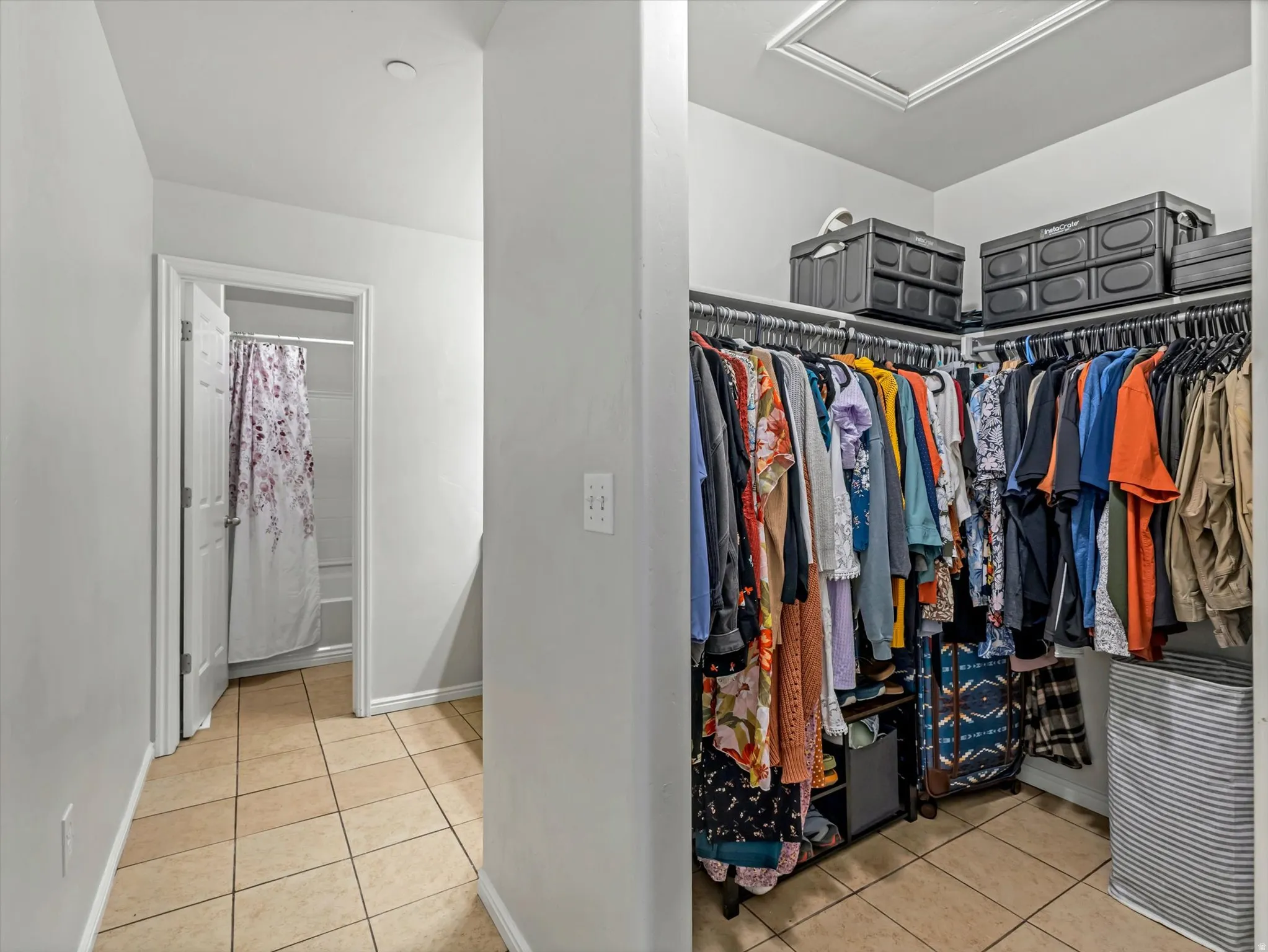 Spacious walk-in closet featuring extensive rod storage, overhead shelving, tile flooring, and recessed ceiling lighting