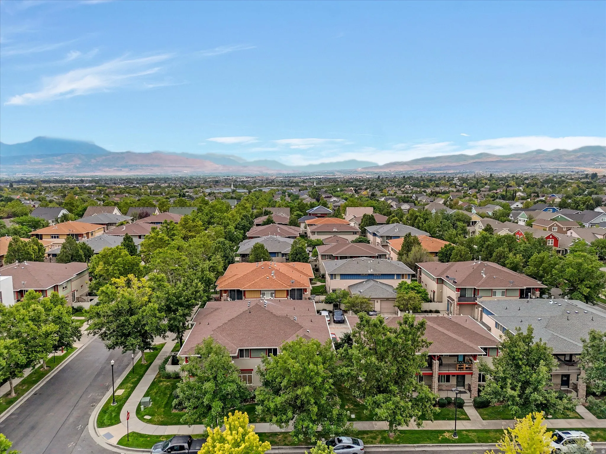 Aerial view of the property and community featuring custom-built homes with varied architectural styles, mature landscaping throughout the neighborhood, and mountain backdrop