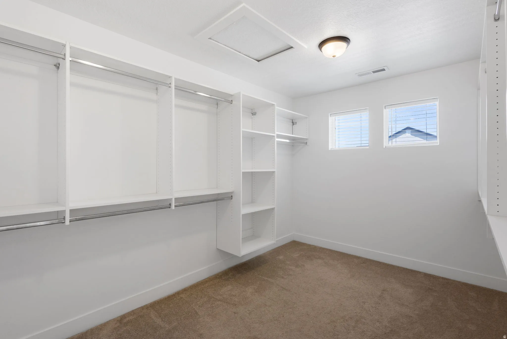 Primary Bedroom has a spacious walk-in closet featuring custom built-in shelving and hanging systems with polished chrome hardware, wood-finish shelving, and abundant storage throughout