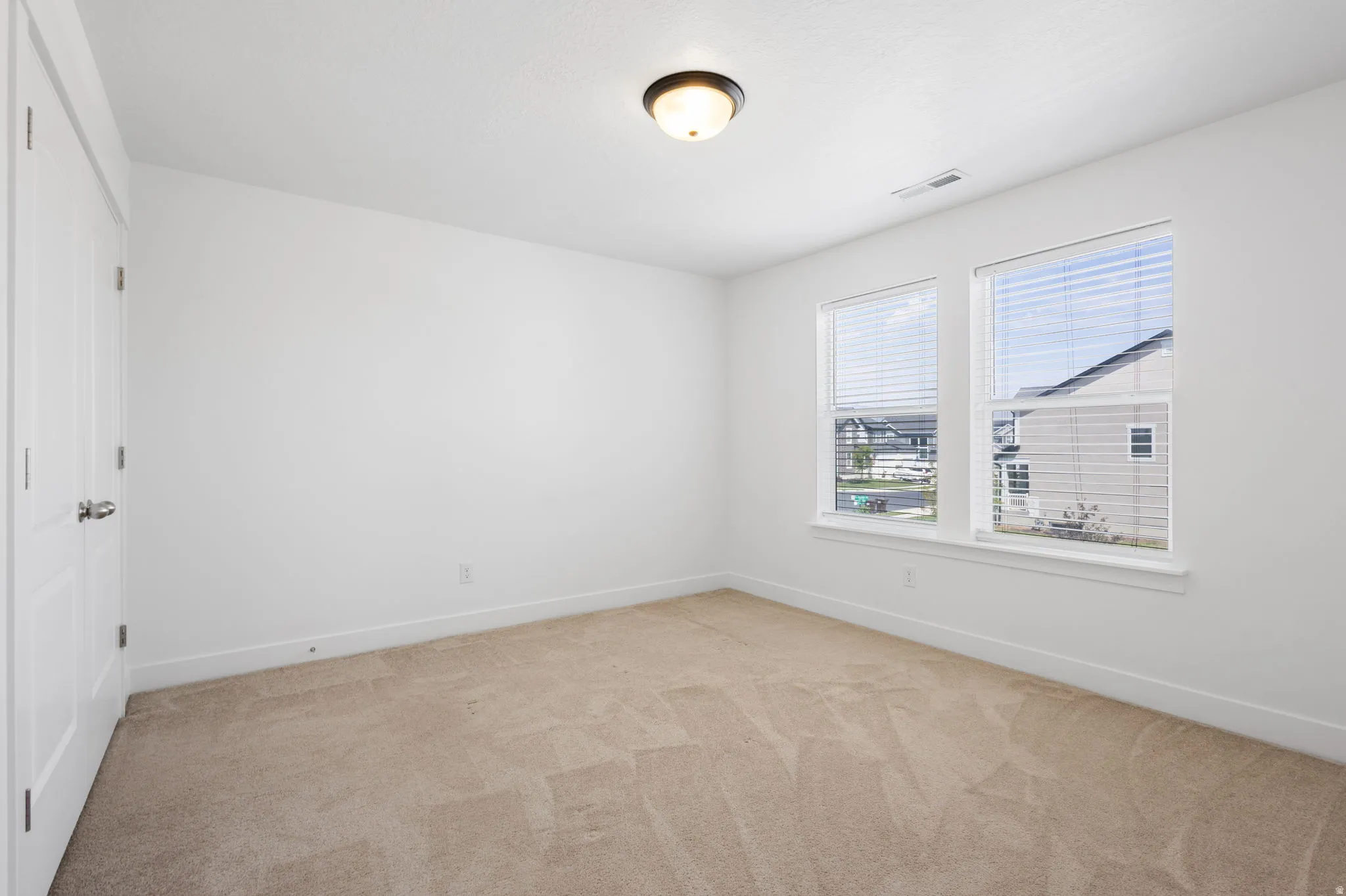 Neutral tone carpet, white painted walls, two paneled doors, and dual windows with blinds