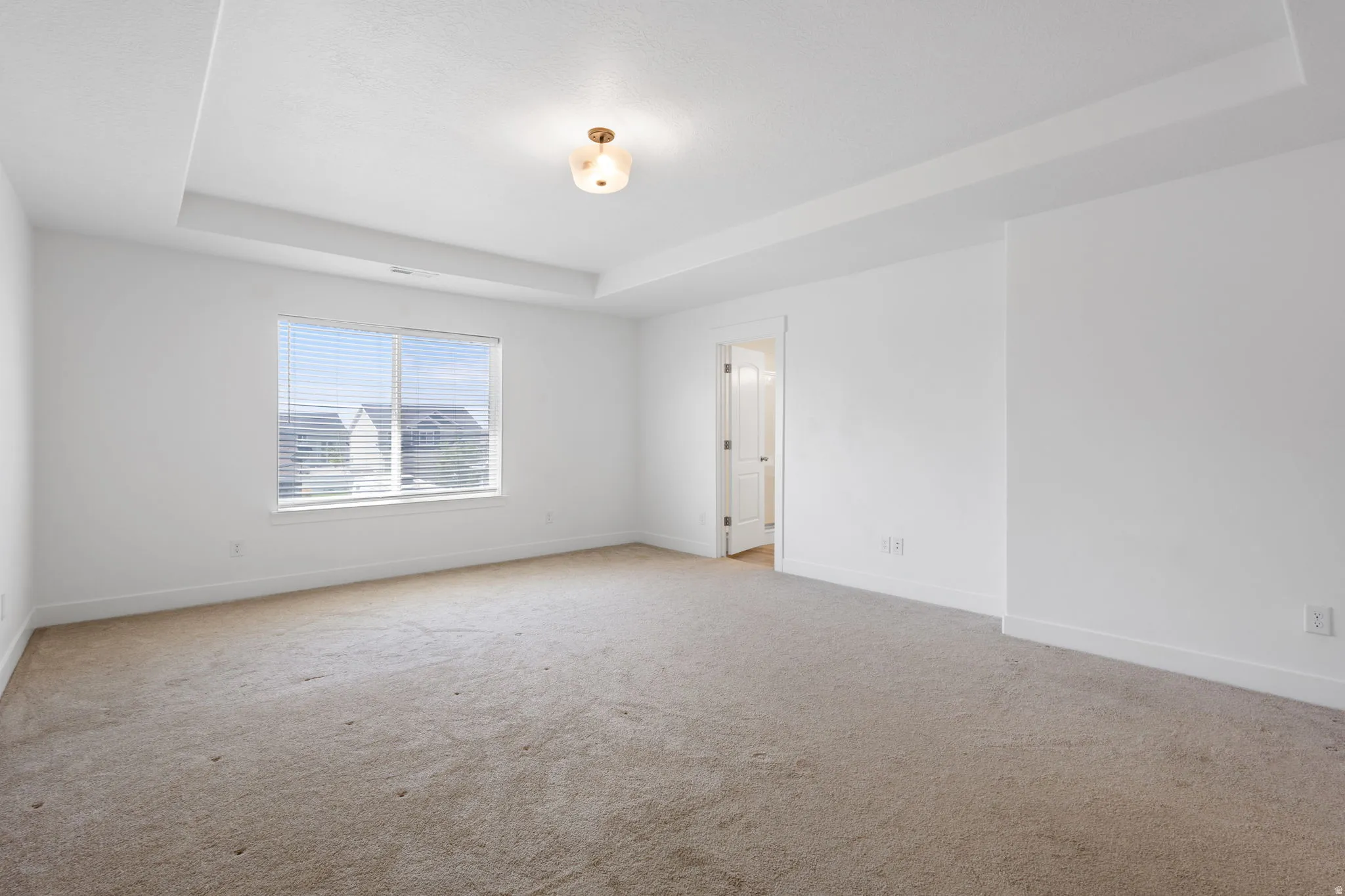 Primary Bedroom with tray ceiling with a central flush mount light fixture