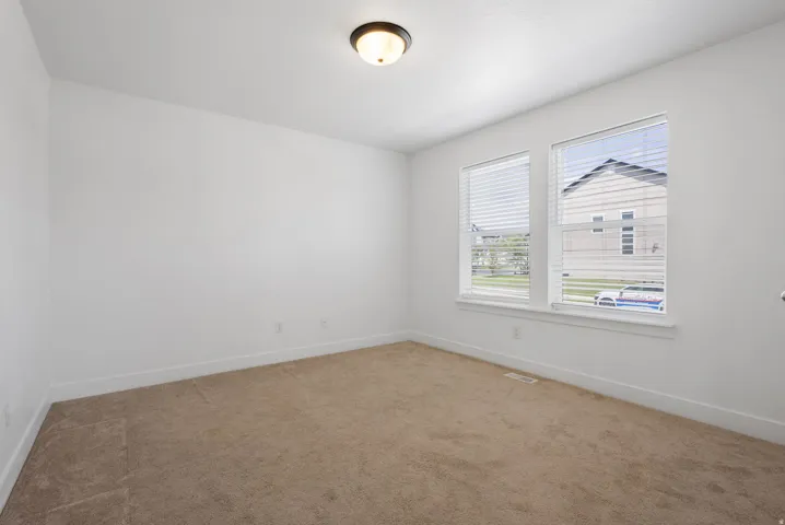 Soft carpet flooring, white painted walls, two windows, and a flush mount ceiling light