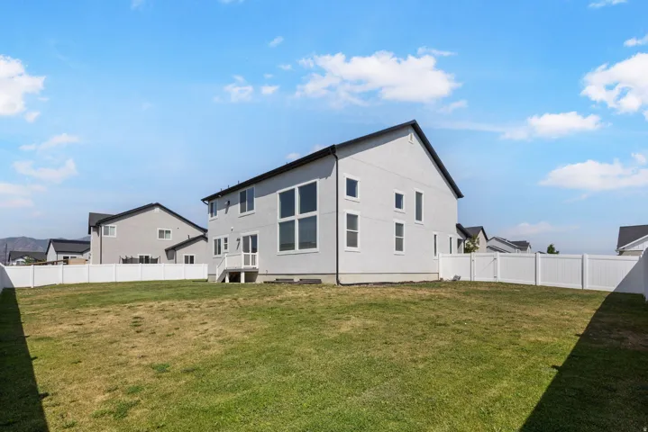 Expansive backyard with a full white vinyl privacy fence, a two-story exterior, and a mountain backdrop