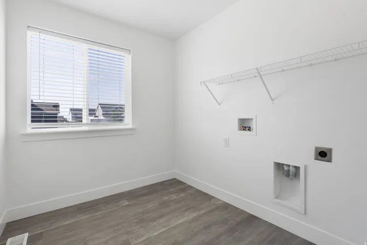 Bright room with wood-finish flooring, a white window with blinds, and white wire shelving