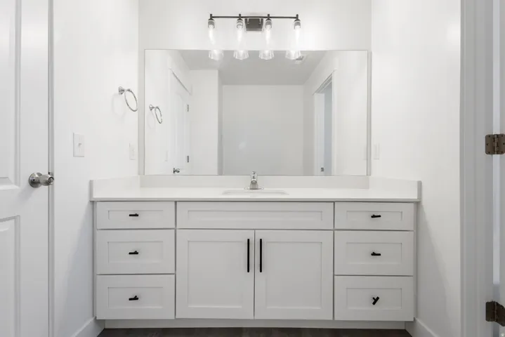 Spa-inspired primary bathroom vanity featuring a double-sink white cabinetry with ample storage, brushed nickel hardware, and a wide quartz countertop