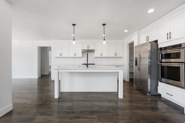 Kitchen featuring white cabinetry, stainless steel appliances, a center island with pendant lighting, and wood-finish flooring