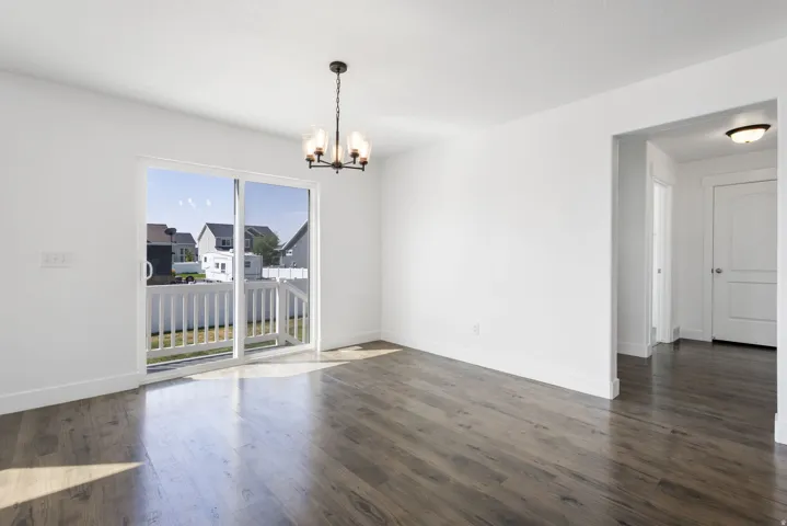 Bright and spacious living area featuring gleaming wood-finish flooring throughout, expansive glass sliding doors with railing access, and abundant natural light