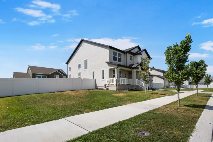 Modern two-story residence featuring a clean architectural design with dark trim accents, complemented by a spacious front lawn with mature landscaping