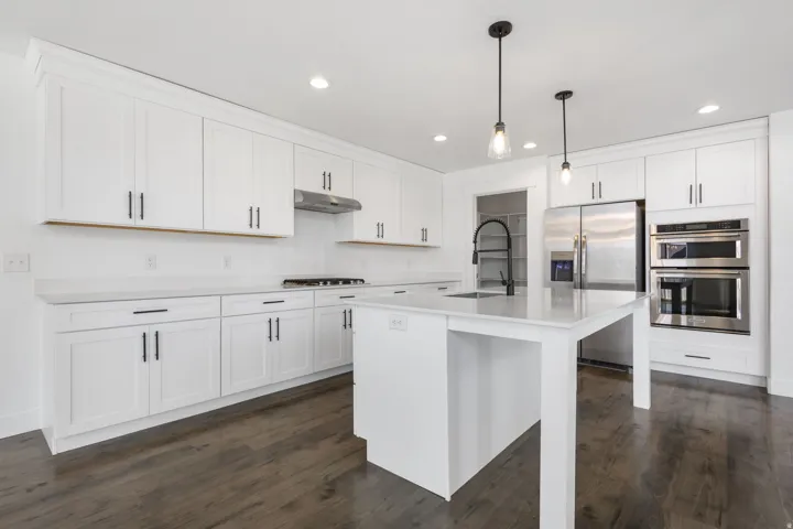 Kitchen featuring white cabinetry, light countertops, wood-finish flooring, recessed lighting, and a kitchen island with a sink