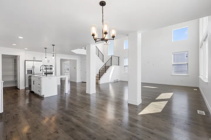 Open-concept main level featuring wood-finish flooring, a two-story ceiling, and a modern kitchen with stainless steel appliances