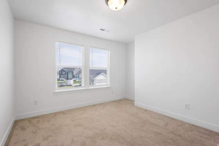 Carpeted room featuring dual windows, a ceiling-mounted light fixture, and neutral white walls