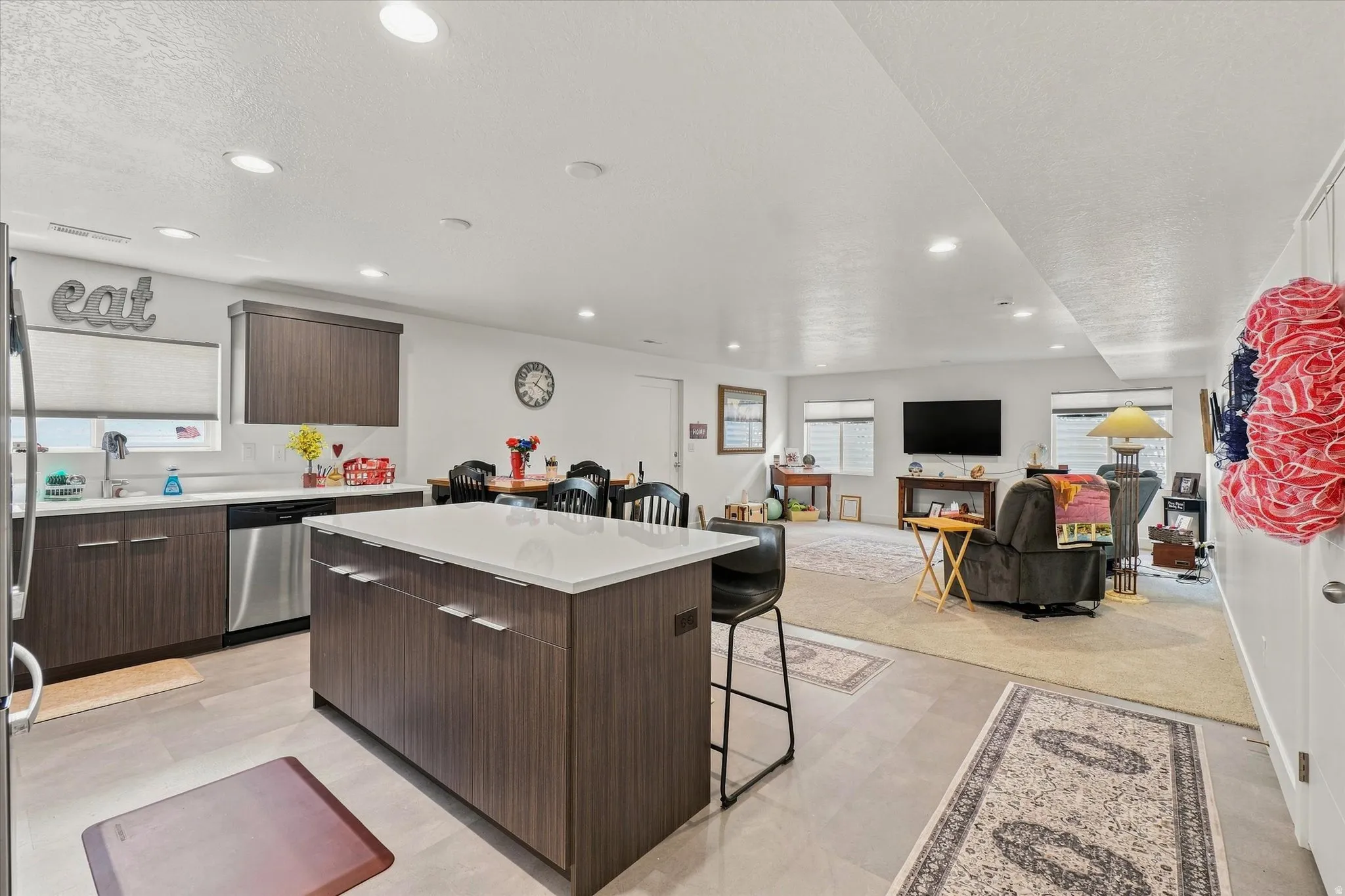 Kitchen featuring a center island with countertop seating, wood-finish cabinetry, stainless steel appliances, and recessed lighting