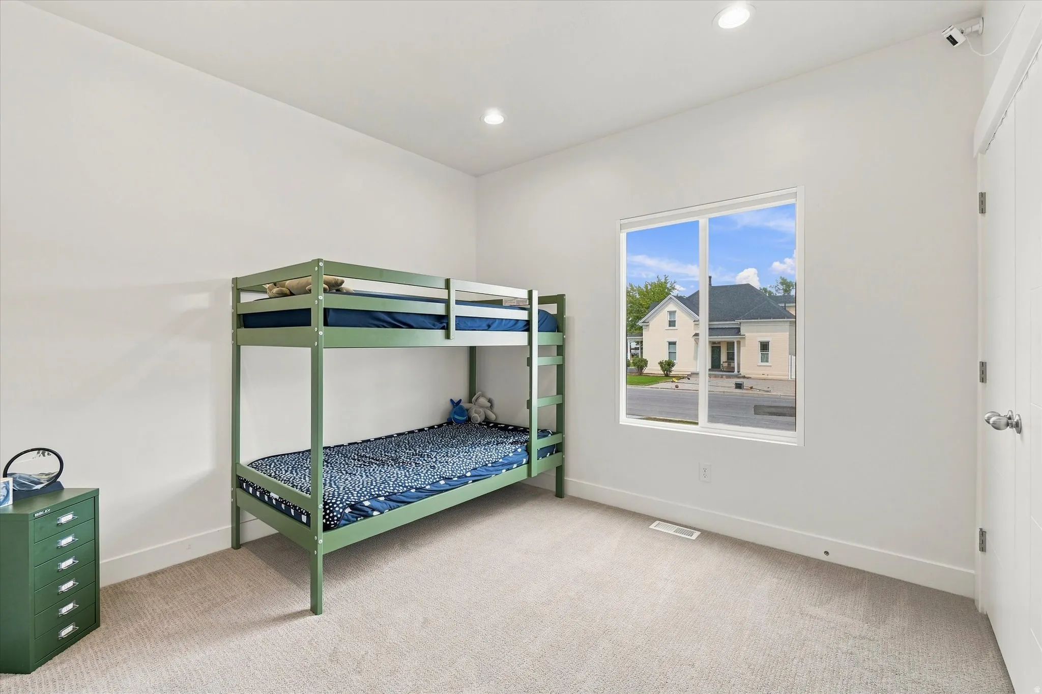 Recessed ceiling lighting, white walls, carpet flooring, and a white interior door with a silver knob