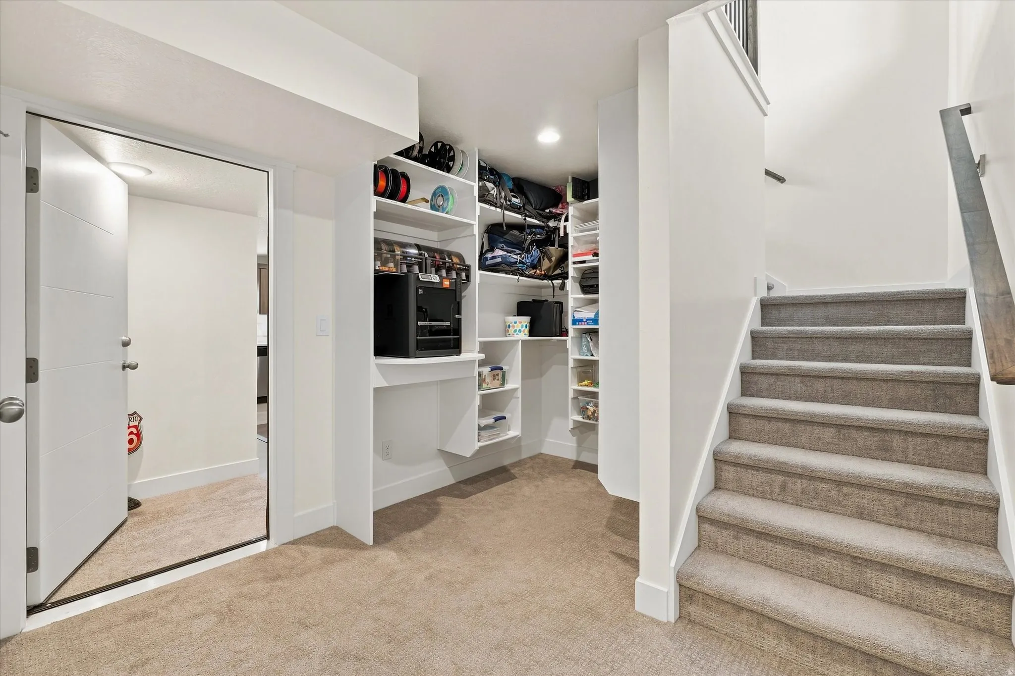 Carpeted staircase with a wood-finish handrail, built-in shelving, recessed lighting, and a paneled door