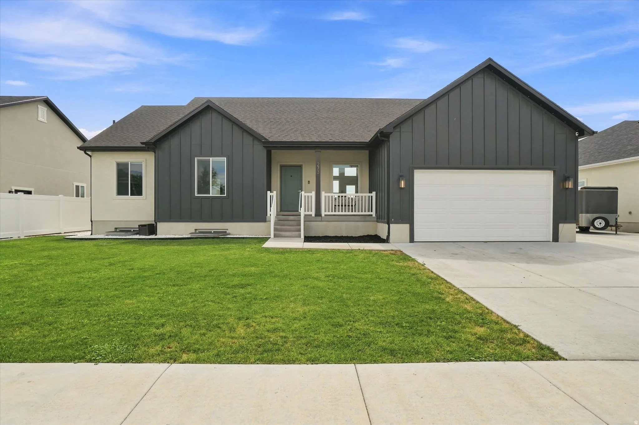 Modern exterior featuring vertical board and batten siding, stucco accents, and a covered entry porch with white railings