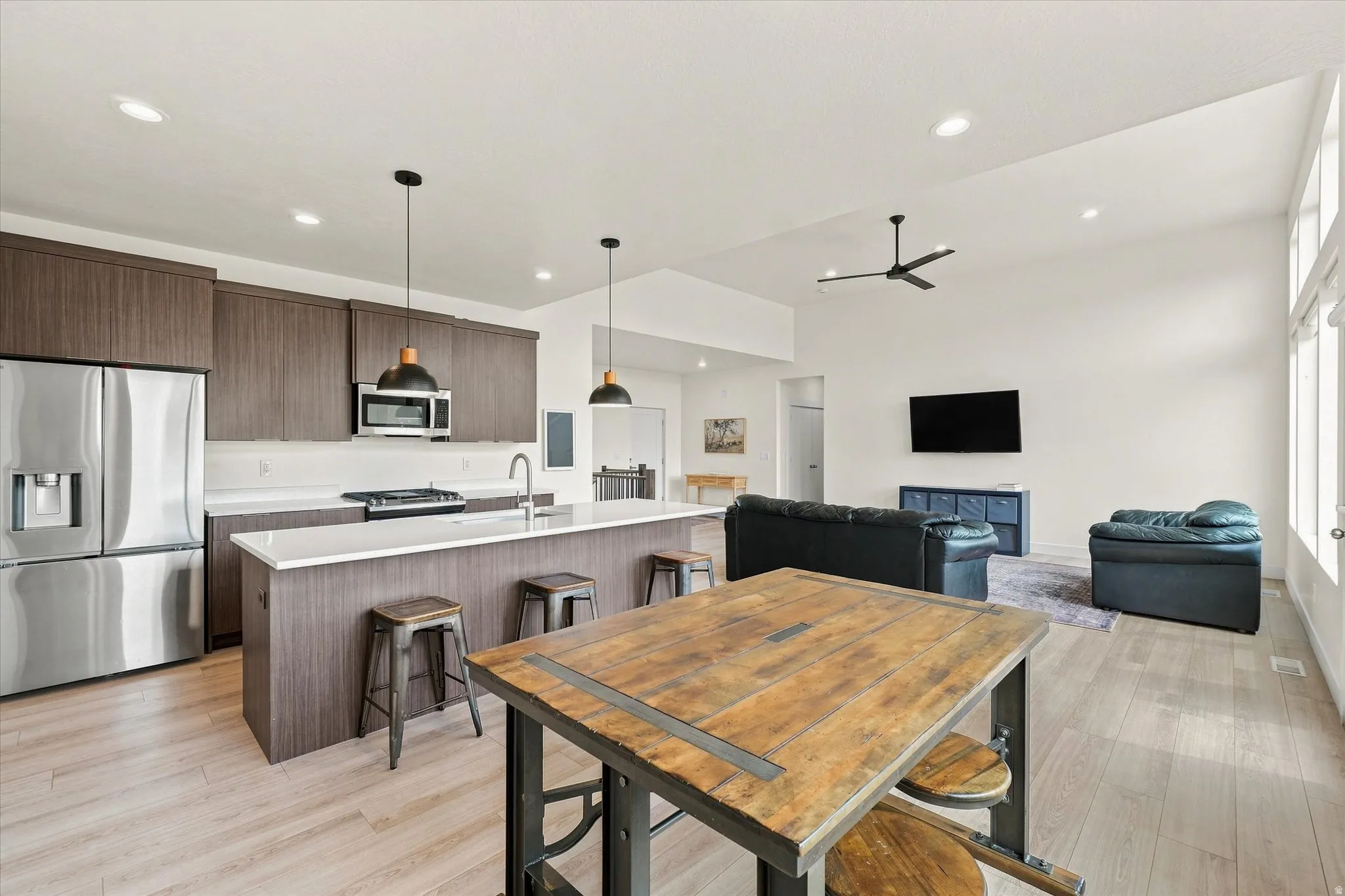 Open-concept living space with wood-finish flooring, vaulted ceilings, and recessed lighting