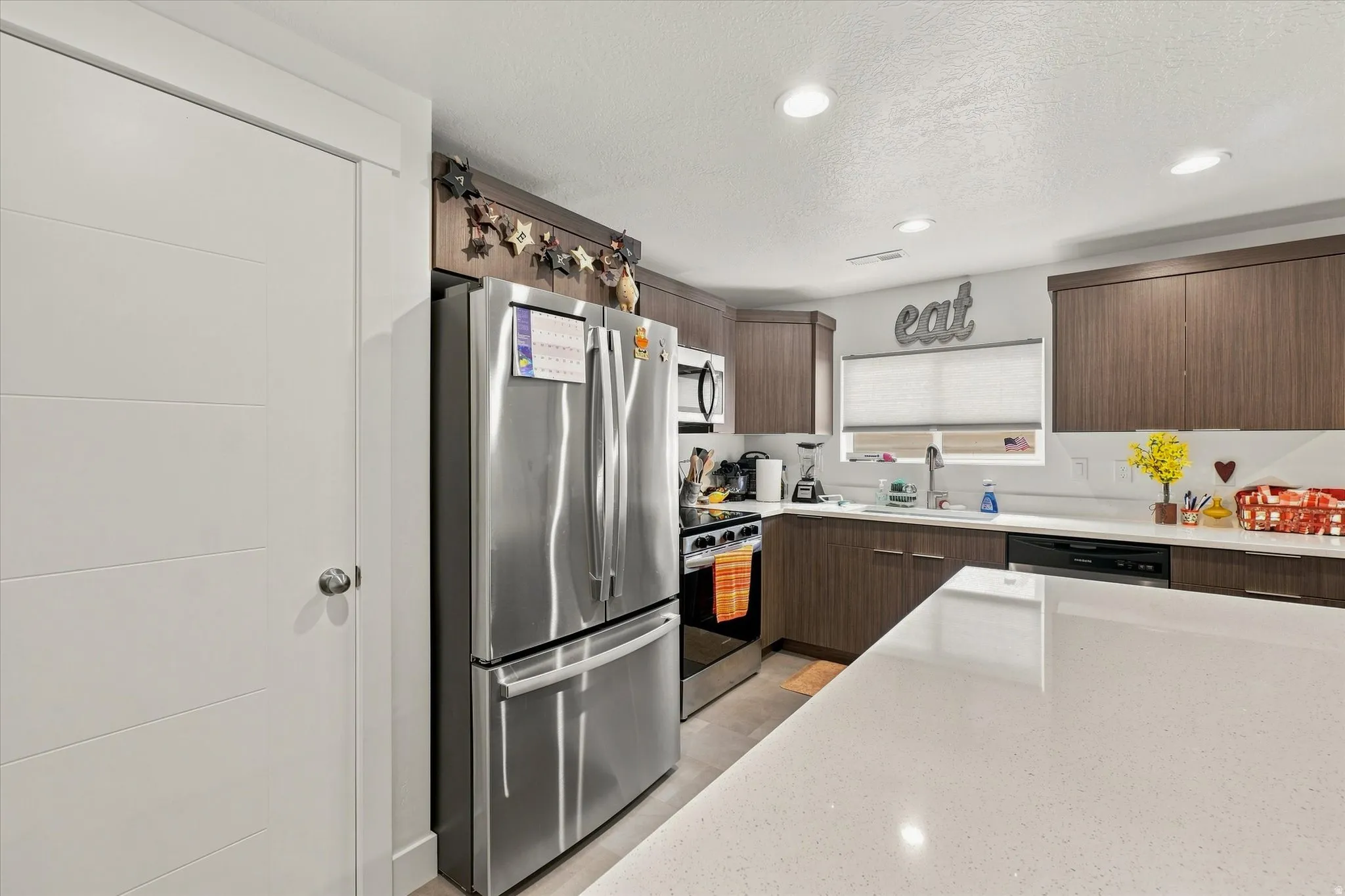 Stainless steel appliances, recessed lighting, wood-finish cabinetry, white countertop, and white subway tile backsplash