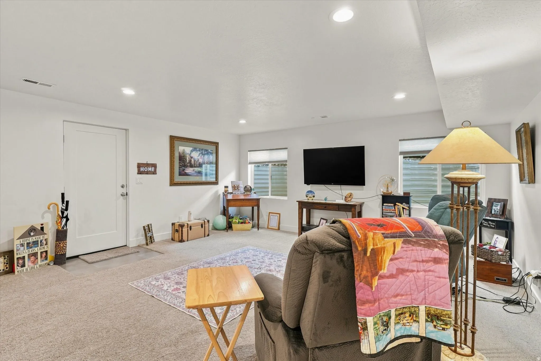 Recessed ceiling lighting, multiple windows, light-colored walls, and carpeted flooring