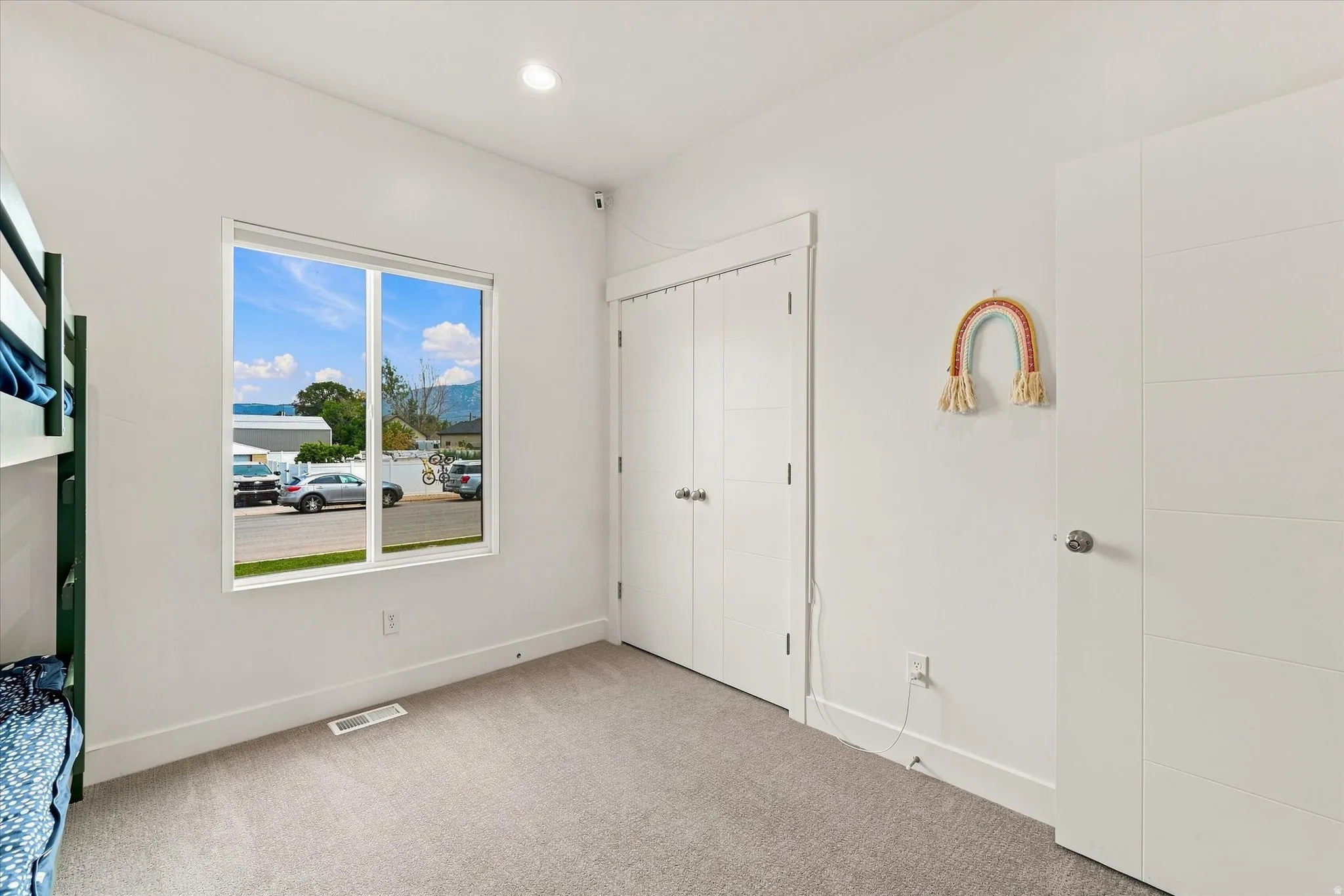 Recessed lighting, light gray carpeting, crisp white walls, white trim, and a white interior door with horizontal paneling