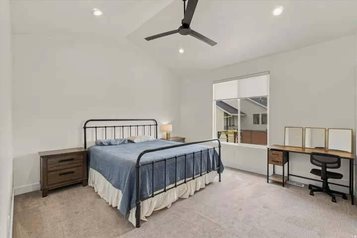 Vaulted ceiling with recessed lighting, ceiling fan, large window, and carpeted flooring