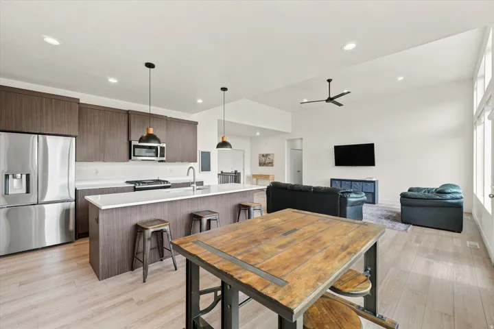 Open-concept living space with wood-finish flooring, vaulted ceilings, and recessed lighting