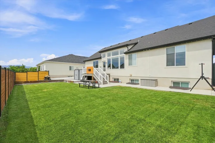 Expansive green lawn with a solid wood and metal fence