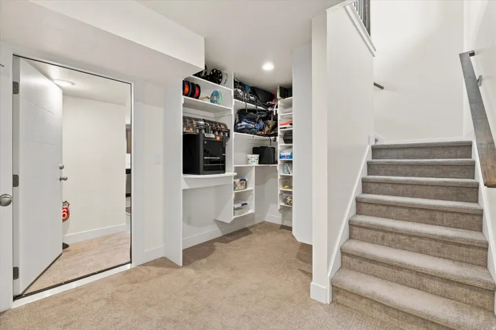 Carpeted staircase with a wood-finish handrail, built-in shelving, recessed lighting, and a paneled door