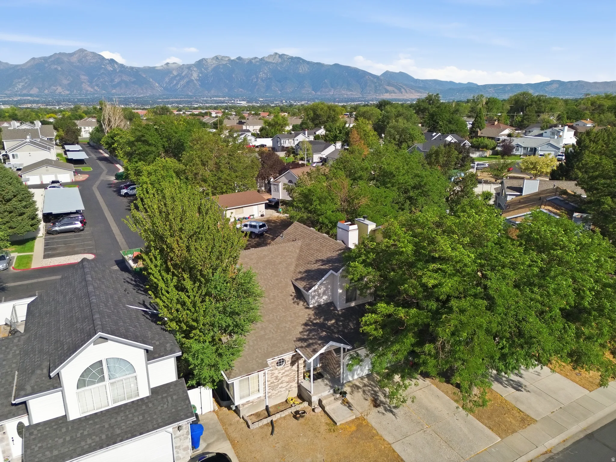 Mountain backdrop, mature trees, residential street, gabled roofline, front porch