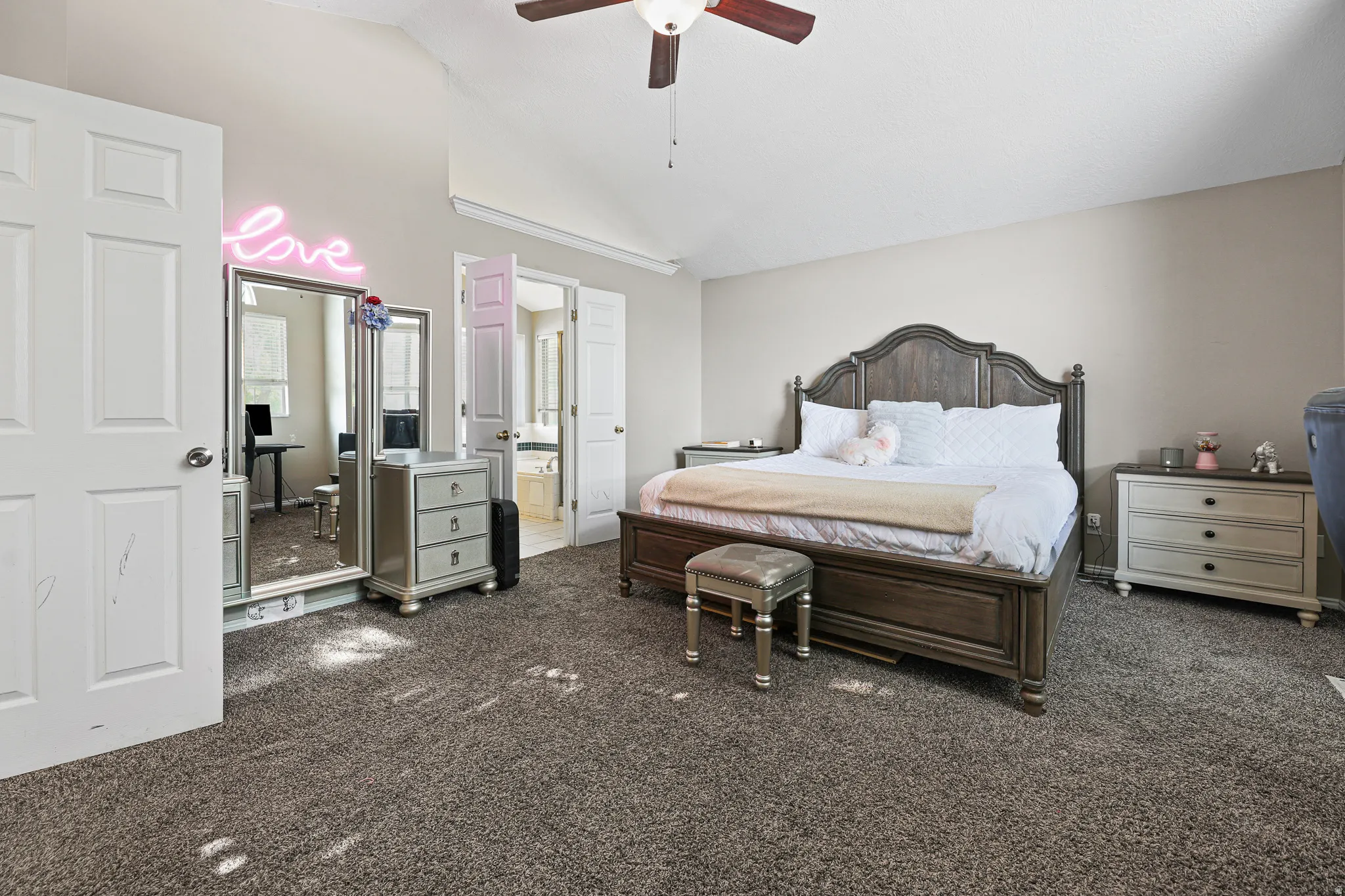 Vaulted ceiling with ceiling fan, neutral wall tones, and carpeted flooring