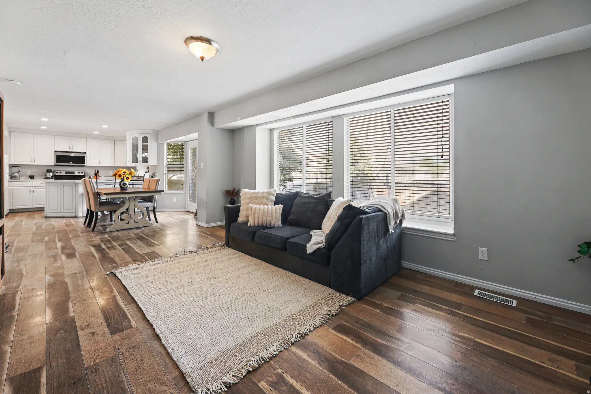 Wood-finish flooring throughout, white kitchen cabinetry, recessed lighting, and a kitchen appliance package