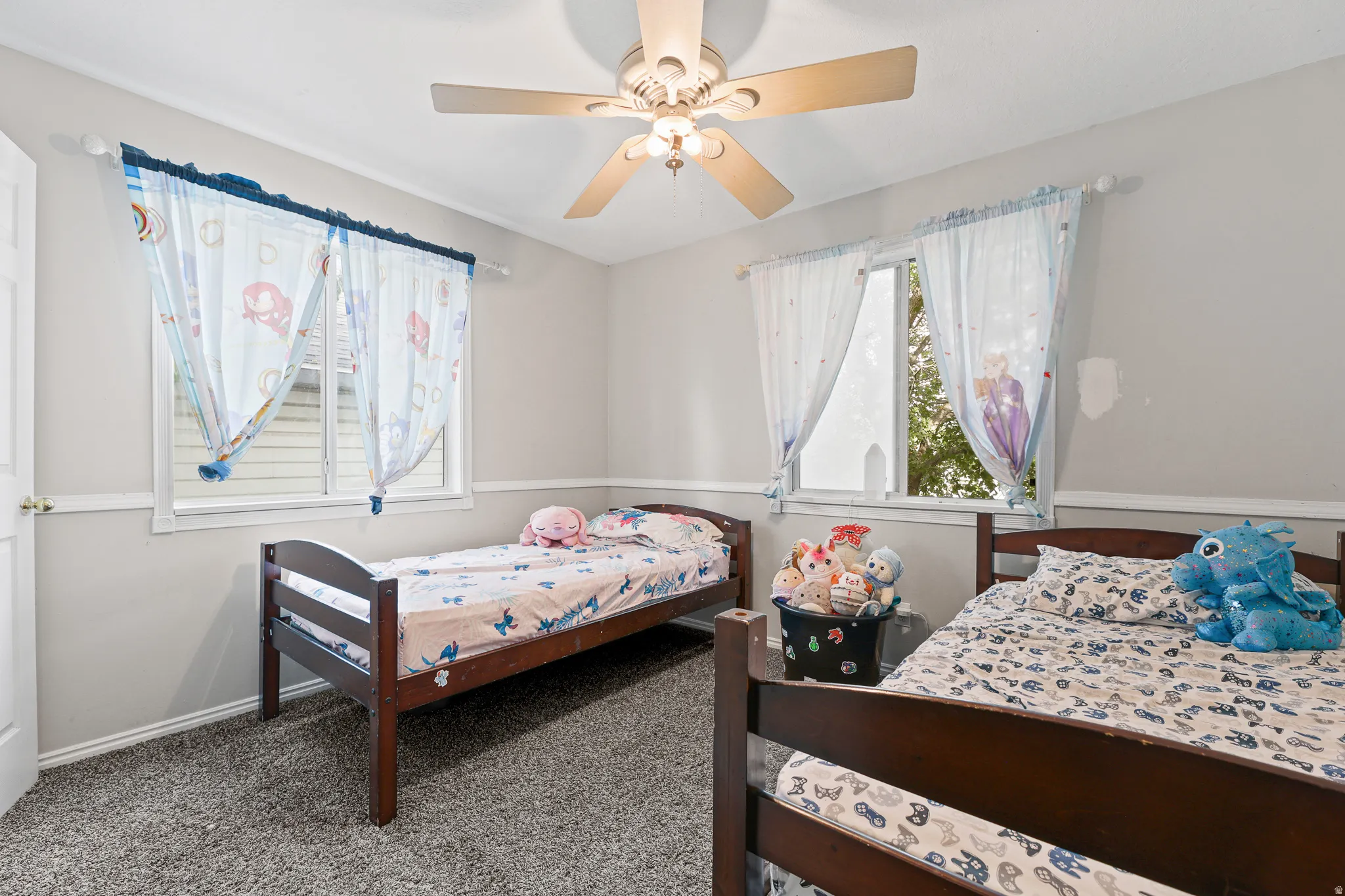 Textured carpeting, two windows with white trim, chair rail molding, and a ceiling fan with integrated lighting