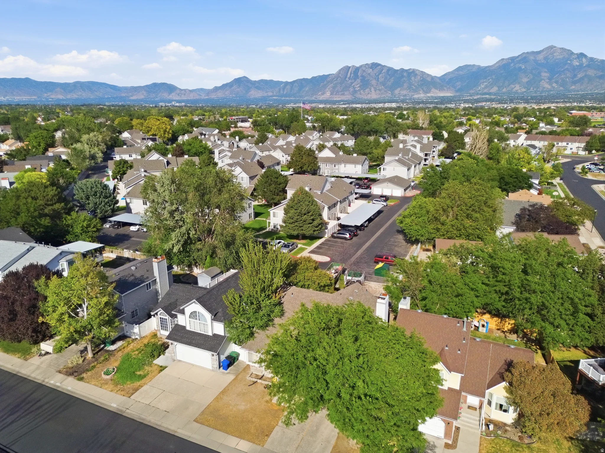 Residential community with mature landscaping, paved roads, and mountain backdrop
