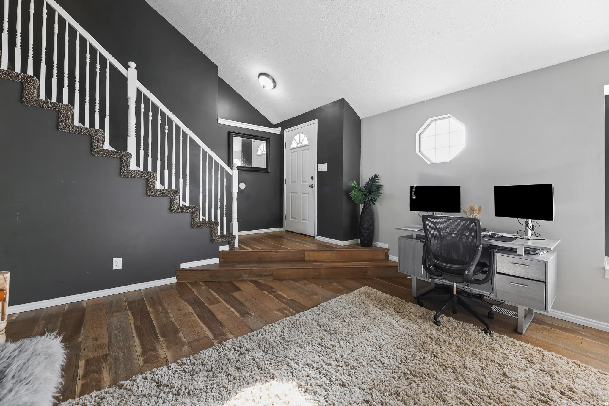 Wood-finish flooring, white spindle staircase, and a distinct octagonal window